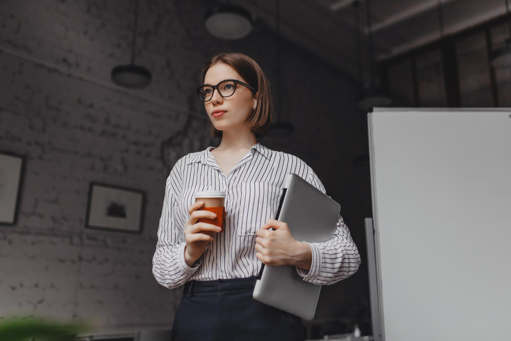 /upl/portrait-of-intelligent-woman-in-glasses-holding-cup-of-tea-employee-in-stylish-outfit-posing-with-laptop.jpg